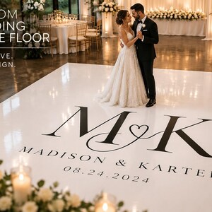 May include: A white custom wedding dance floor featuring the black monogram M&K with a heart symbol, the names Madison & Karter, and the date 08.24.2024. The text CUSTOM WEDDING DANCE FLOOR and YOUR LOVE. OUR DESIGN. appear in the upper left corner.