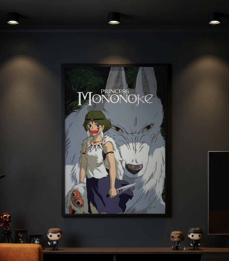 May include: A framed poster featuring the title Princess Mononoke in white text. The artwork displays a character with short green hair, a white top, and a dark skirt, holding a knife. Behind the character is a large white wolf with dark eyes.