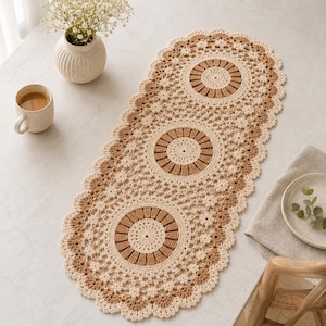 May include: Cream and brown crochet table runner with three circular designs. The runner has a scalloped edge and is made of a soft, textured yarn. The design features a repeating pattern of openwork and solid circles.
