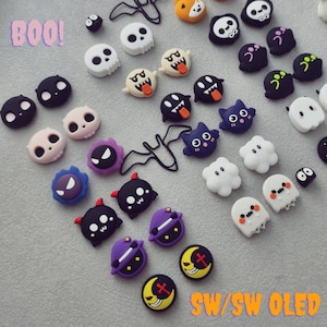 May include: A collection of small, colorful, decorative charms featuring various Halloween-themed characters including skulls, ghosts, bats, and crescent moons. The text BOO is printed in the top left corner and SW/SW OLED in the bottom right corner.