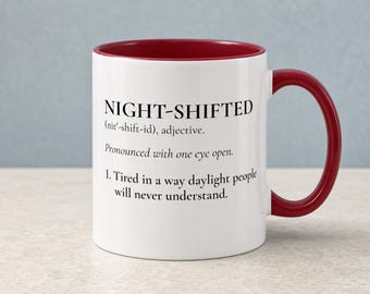 May include: A white ceramic mug with a dark red interior and handle. The front features black text that reads: NIGHT-SHIFTED (nit'-shift-id), adjective. Pronounced with one eye open. 1. Tired in a way daylight people will never understand.