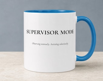 May include: A white ceramic mug with a bright blue interior and handle. The front features the black text SUPERVISOR MODE in a bold serif font, followed by the smaller black text Observing intensely. Assisting selectively. centered below.