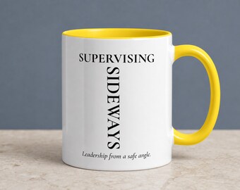 May include: A white ceramic mug with a bright yellow interior and handle. The front features the black text SUPERVISING written horizontally, with SIDEWAYS written vertically intersecting it, and the phrase Leadership from a safe angle below.