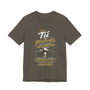 Puede incluir: Camiseta verde oliva con un diseño gráfico dorado y blanco. El diseño incluye el texto "Tú me guiarás" y una ilustración de cruz, montañas y sol. El texto también incluye "Salmo 73:23-24".