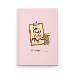 Può includere: Un quaderno rosa chiaro con la scritta "tiny tasks BIG FEELINGS" sulla copertina. Un orsetto dei cartoni animati con un cappello da infermiera tiene in mano una cartella con il testo. La parte inferiore del quaderno riporta la scritta "This belongs to _".
