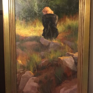 Pode incluir: Uma pintura de uma mulher com um vestido preto sentada em rochas num campo. A mulher tem a cabeça baixa e o cabelo é castanho-avermelhado. O fundo é uma paisagem verde e castanha desfocada.