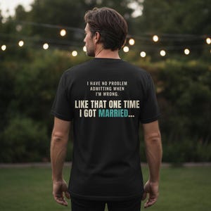 May include: A black short-sleeved t-shirt featuring white and teal text on the back that reads: I HAVE NO PROBLEM ADMITTING WHEN I'M WRONG. LIKE THAT ONE TIME I GOT MARRIED...
