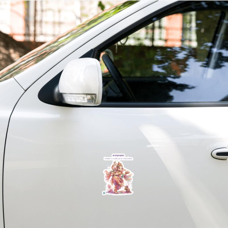 May include: A white car door featuring a rectangular sticker with a colorful illustration of the deity Ganesha. The sticker includes the text "GANAPATI" and "Lord of wisdom and success" in a purple font, with a small letter D in the corner.