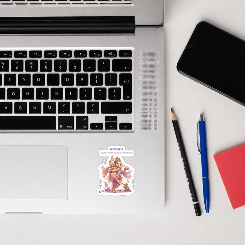 May include: A die-cut sticker featuring a colorful illustration of the deity Ganesha, depicted with multiple arms and an elephant head, standing near a small mouse. The text above reads Ganesha and Remove obstacles, invite abundance.