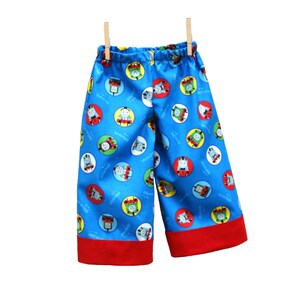 May include: Blue and red children's shorts with a repeating pattern of cartoon train characters in circles.