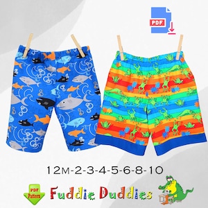 May include: PDF pattern for boys' shorts in two designs. One design features blue shorts with a shark and fish print. The other design features red shorts with a rainbow stripe and frog print. The pattern includes sizes 12M-10.