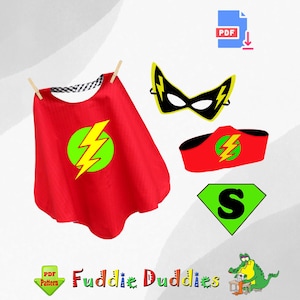 May include: A red superhero cape with a green circle and yellow lightning bolt design, plus a matching mask, headband, and a green diamond with a black "S". The image also includes the text "Fuddie Duddies".