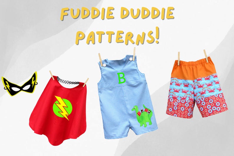May include: Three different clothing items for children, hanging on a clothesline. A red cape with a yellow lightning bolt, a blue and white gingham overall with a green dinosaur applique, and orange and red patterned shorts with a crab design.