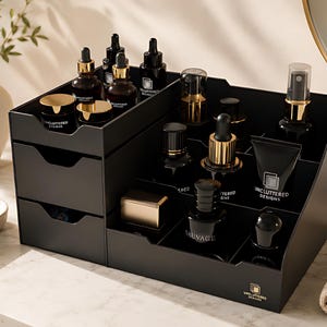 May include: A black cosmetic organizer with multiple compartments and two drawers. The organizer holds various skincare products in dark bottles with gold accents. The text "UNCLUTTERED DESIGNS" is visible on the products and the organizer.