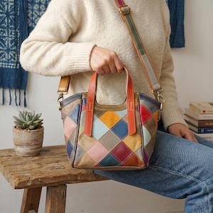 May include: A multi-colored leather handbag featuring a diamond-shaped patchwork pattern in shades of orange, blue, yellow, pink, red, and brown. The bag includes two orange top handles and a detachable, adjustable shoulder strap with metal hardware.