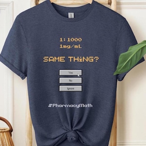 Könnte beinhalten: Ein dunkelblaues Kurzarm-T-Shirt mit gelbem, verpixeltem Text, der 1:1000 1mg/mL SAME THING? lautet, gefolgt von drei grauen rechteckigen Schaltflächen mit der Beschriftung Yes, No und Ignore, einem Mauszeiger auf Yes und #PharmacyMath unten.