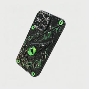 May include: A black smartphone case featuring a textured, raised design of intertwined dark vines and multiple bright green, realistic reptilian eyes with vertical pupils scattered across the surface, surrounding the camera lens cutout area.