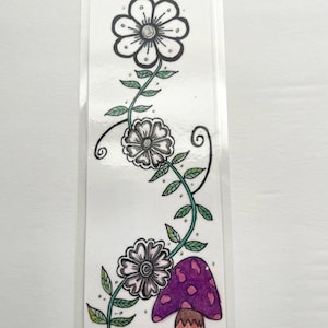 Könnte beinhalten: Ein rechteckiges Lesezeichen mit einer handgezeichneten Illustration einer gewundenen grünen Ranke mit drei schwarz-weißen Blumen und einem violetten Pilz mit rosa Punkten an der Basis. Das Design befindet sich in einer klaren, glänzenden Laminathülle.