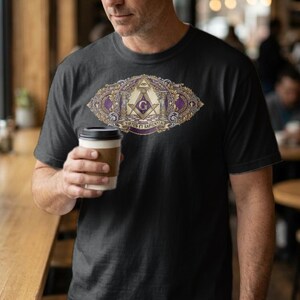 May include: A black short-sleeved t-shirt featuring a central graphic design with a purple and gold oval frame. The design includes a square and compass symbol, a letter G, and the Latin text VIRTUS ET SAPIENTIA printed in a decorative style.