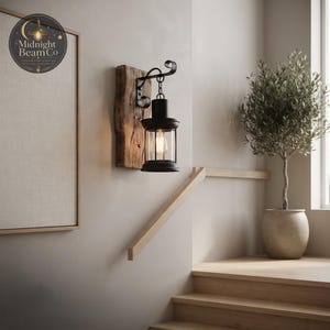 Product specification image for the Midnight Beam Co rustic wall lantern, showing the 330mm height and 150mm width measurements, with material callouts for powder-coated metal, reclaimed wood, and clear glass enclosure.