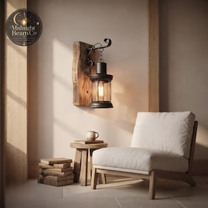 Close-up of a farmhouse lantern wall sconce showing the ornate scrolled iron hook, the black chain links, and the black cylindrical steel lantern body with a warm Edison-style filament bulb visible through the clear tempered glass panels.