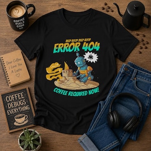 May include: Black t-shirt with a robot graphic and the text "ERROR 404 COFFEE REQUIRED NOW!". The robot is building a sandcastle. Other items include a coffee cup, a notebook, a sign, and a pair of blue jeans.