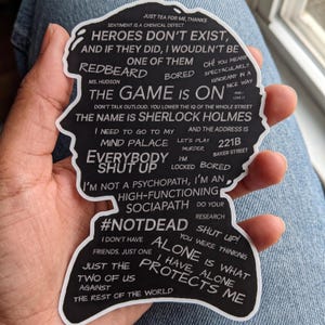 May include: A black die-cut sticker shaped like a silhouette of a head, featuring white text quotes from Sherlock Holmes including "The game is on," "221B Baker Street," "I'm a high-functioning sociopath," and "Mind palace" printed across the surface.
