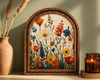 May include: An arched wooden frame containing a textured painting of a wildflower meadow. The artwork features vibrant red, orange, yellow, and blue flowers against a cream background. The frame has a dark brown finish and a rounded top edge.