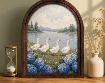 May include: An arched wooden frame containing an oil painting of four white geese walking in a line along a grassy bank. The scene features a calm lake, distant green hills, a cloudy sky, and clusters of blue hydrangea flowers in the foreground.