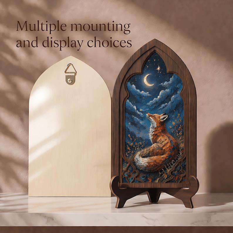 May include: An arched wooden frame containing a painting of a fox looking up at a crescent moon in a dark blue cloudy sky. The frame has a dark wood finish and sits on a matching stand. A light wood back panel with a metal hanger is also shown.