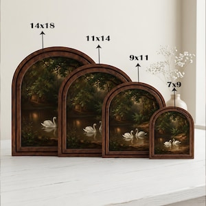 Puede incluir: Cuatro piezas de arte mural arqueadas en marcos de madera oscura, cada una con un estanque sereno con cisnes blancos y &aacute;rboles verdes. Los tama&ntilde;os se indican como 14x18, 11x14, 9x11 y 7x9 pulgadas para cada cuadro individual.