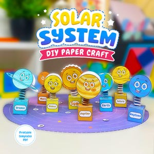 Könnte beinhalten: Ein DIY-Papierbastelset, das das Sonnensystem mit cartoonartigen Planeten und der Sonne auf Federn an quadratischen Sockeln darstellt. Jeder Sockel ist mit dem Namen des Himmelskörpers beschriftet. Das Set steht auf einer runden violetten Matte.