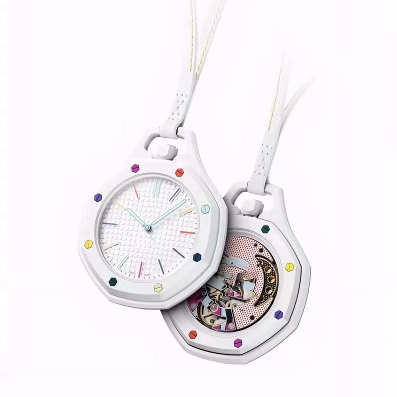 May include: Two white pocket watches with octagonal cases and white leather straps. The left watch features a white textured dial with multi-colored hour markers. The right watch displays an exposed mechanical movement with a moon phase complication.