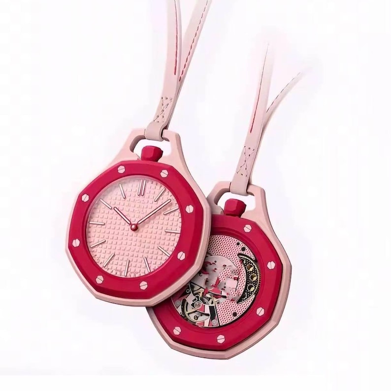 May include: Two octagonal pocket watches with light pink straps. The left watch features a light pink textured dial with silver hands. The right watch displays an exposed mechanical movement with a crescent-shaped gear and a pink perforated plate.