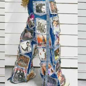 Puede incluir: Vaqueros de mezclilla azul con un collage de parches rectangulares con im&aacute;genes impresas y texto, incluido el nombre Usher. Los vaqueros tienen una silueta de pierna ancha, bordes deshilachados en los parches y una tira larga de mezclilla.