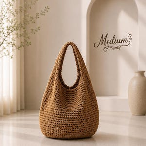 Puede incluir: Un bolso hobo de ganchillo de color tostado, de tama&ntilde;o mediano, con un patr&oacute;n de punto tejido y texturizado. El bolso cuenta con un asa integrada &uacute;nica y una silueta redondeada y holgada. La palabra Medium aparece escrita en cursiva.
