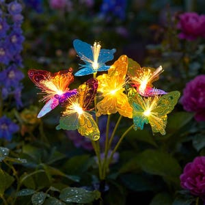 Pode incluir: Um conjunto de estacas de jardim com borboletas iluminadas em várias cores, incluindo azul, laranja, amarelo e verde. Cada borboleta tem um centro brilhante e asas de fibra ótica, criando um efeito decorativo.