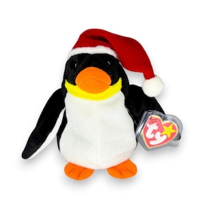 May include: A plush penguin toy featuring black and white fur, an orange beak, and orange feet. The penguin wears a red Santa hat with a white trim and pom-pom. A heart-shaped plastic tag with the red and yellow Ty logo is attached to the wing.