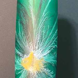Puede incluir: Un jarrón decorativo verde y alto con un diseño de plumas pintadas. El jarrón presenta un centro amarillo y blanco con detalles verdes y negros. El jarrón está sobre una base verde.