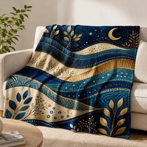 May include: A plush throw blanket featuring a deep navy blue and gold color palette. The design displays wavy, layered bands decorated with botanical leaf motifs, delicate sprigs, a crescent moon, and scattered stars in a metallic gold finish.