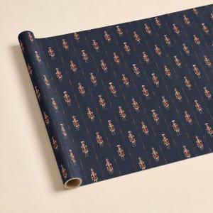 May include: A roll of wrapping paper featuring a repeating pattern of small, detailed nutcracker figures in red, white, and gold uniforms. The nutcrackers are arranged in vertical columns against a solid, dark navy blue background.