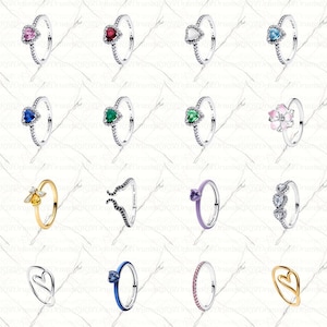 Op de afbeelding: Een verzameling zilveren ringen met verschillende edelstenen en ontwerpen. Sommige ringen hebben hartvormige, ronde of bloemvormige stenen in kleuren als roze, rood, blauw en groen. Andere ringen hebben een bij, een golfpatroon of een rij kleine stenen.