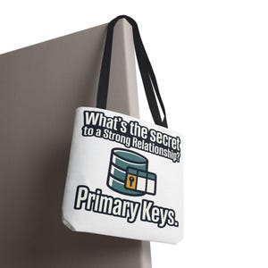 Könnte beinhalten: Weiße Tragetasche mit schwarzen Henkeln. Auf der Tasche steht der Text "What's the secret to a Strong Relationship? Primary Keys." Das Design umfasst ein Datenbank-Symbol und ein Schloss-Symbol. Die Tasche hängt an einer grauen Oberfläche.