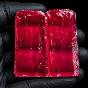 Peut inclure: Deux pierres précieuses rectangulaires, translucides et d'un rouge profond, avec des surfaces lisses et polies présentant des fractures internes visibles. Les pierres ont des coins supérieurs arrondis et des bords droits et nets.