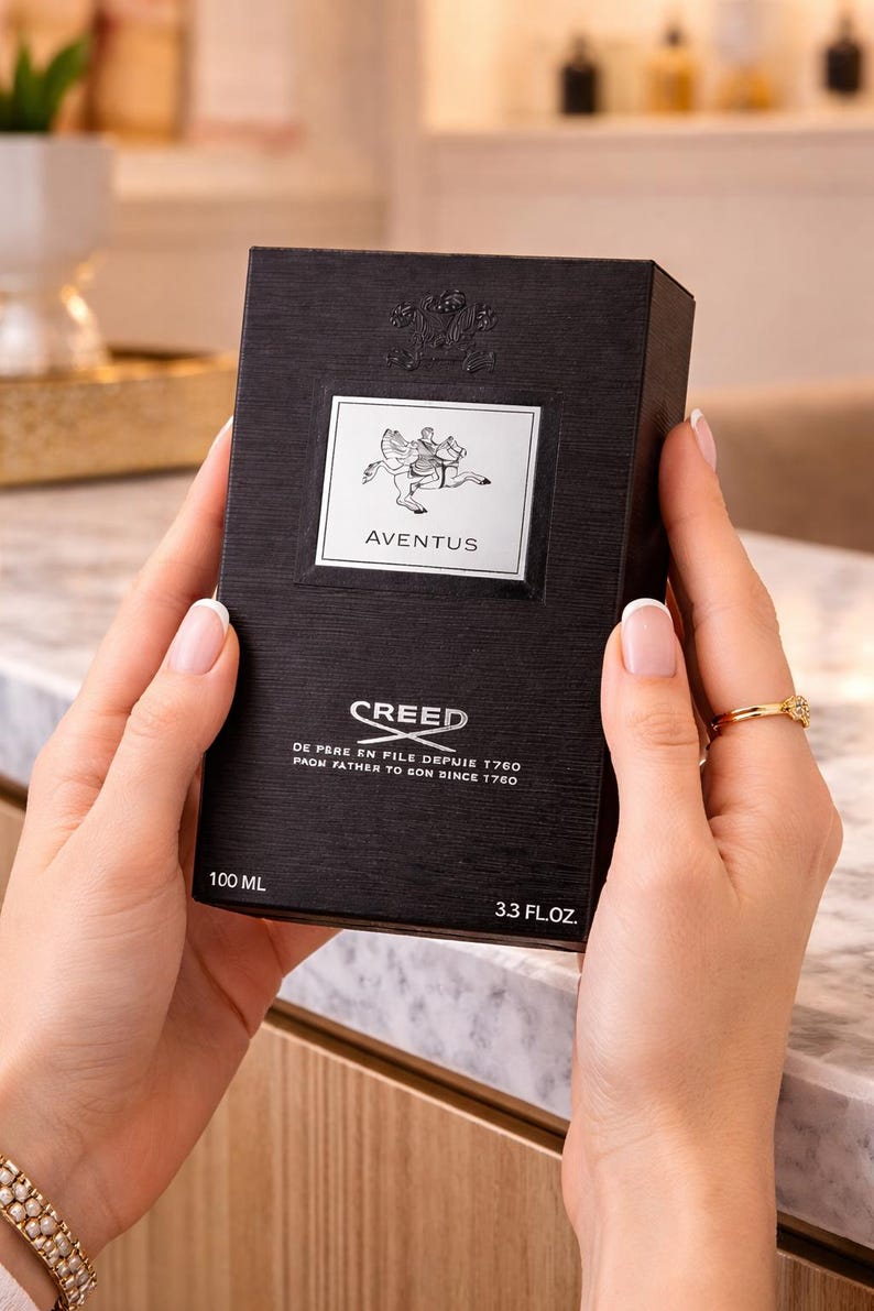 May include: A black rectangular Creed Aventus fragrance box with a textured finish. The front features a silver label with a horse and rider graphic, the text Aventus, Creed, and De Pere En Fils Depuis 1760, 100 ml, and 3.3 fl. oz.