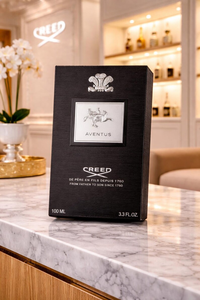 May include: A black rectangular perfume box with a textured finish. It features a silver emblem at the top, a central silver label with the text AVENTUS, and the text CREED DE PERE EN FILS DEPUIS 1760 FROM FATHER TO SON SINCE 1760. It displays 100 ML and 3.3 FL.OZ.