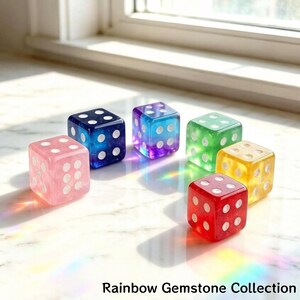 May include: A collection of six colorful gemstone dice. Each die is a different color: pink, blue, purple, green, yellow, and red. The dice have white dots and are arranged on a light-colored surface. Text at the bottom reads "Rainbow Gemstone Collection."