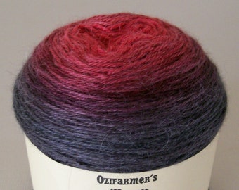 May include: A skein of yarn in a gradient of red to dark grey. The yarn is wrapped around a cardboard tube with a label that reads "Ozifarmer's Market" and "Rapture".