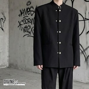 May include: A black jacket with a mandarin collar and a front button closure featuring five silver-toned circular buttons. The jacket has long sleeves and a straight hemline. The text "DIVINE Glamour" is printed in the bottom left corner.