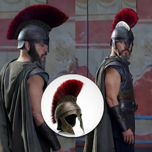 May include: A metallic bronze-toned helmet featuring an ornate embossed band along the crest and a prominent, tall, deep red brush plume extending from the front to the back, designed with a wide face opening and protective cheek guards.